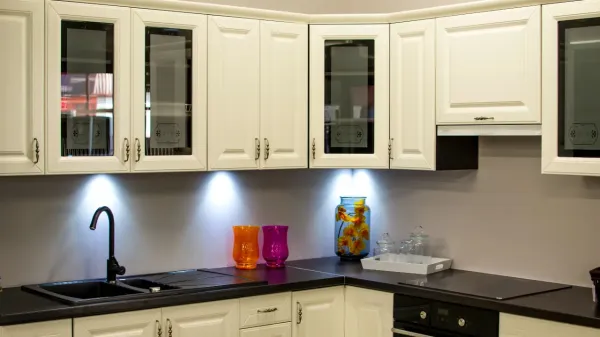 cream kitchen cabinets, some with glass, with black worktops and downlights